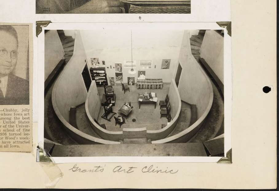 rounded art studio with staircases on either side, artwork hung on the wall, and tables and chairs for working.