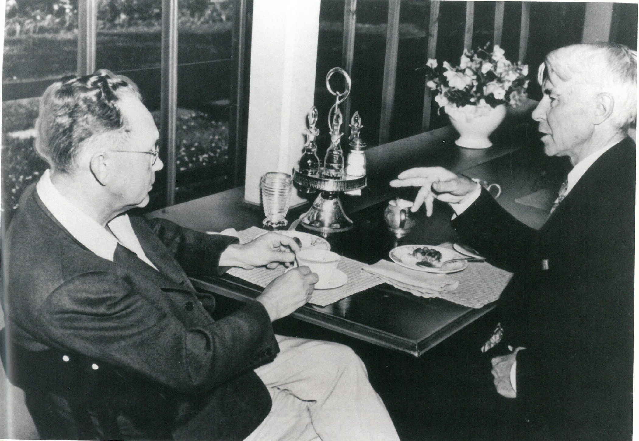 Grant Wood sitting across the table from author Carol Sandburg over tea.
