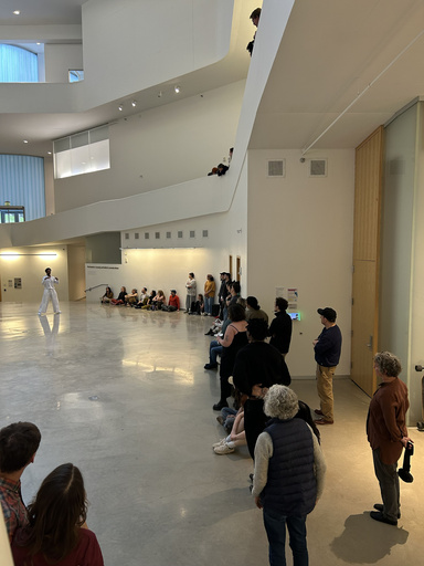 a man dressed in white dances in a white atrium while people watch