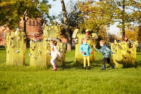 Children laughing and running around the Bee Project mural installation.