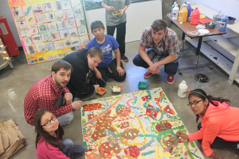 kids paint abstract images on a large canvas on the floor