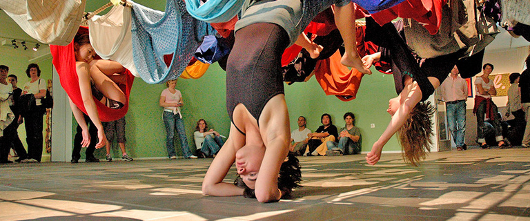 3 people suspended in colorful fabrics