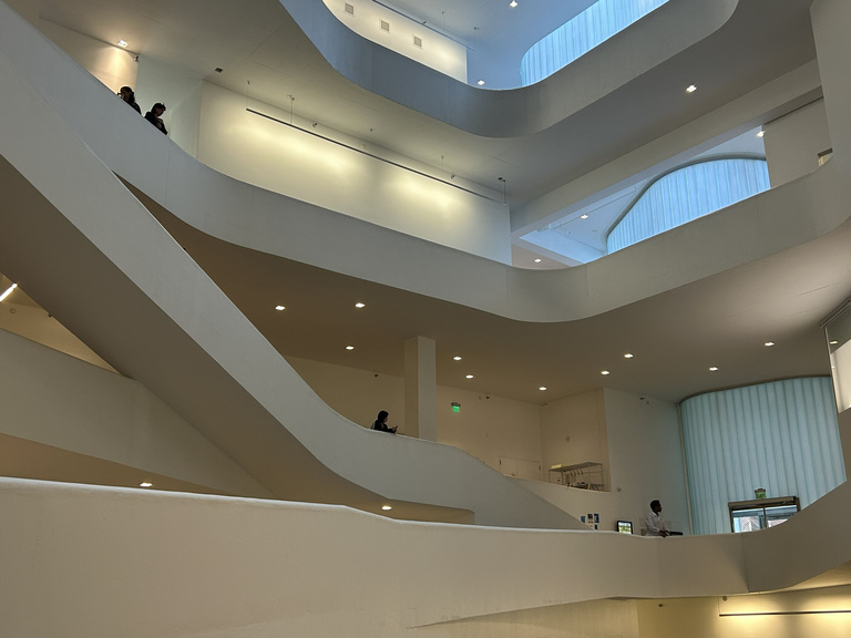 a man dressed in white dances in a white atrium while people watch