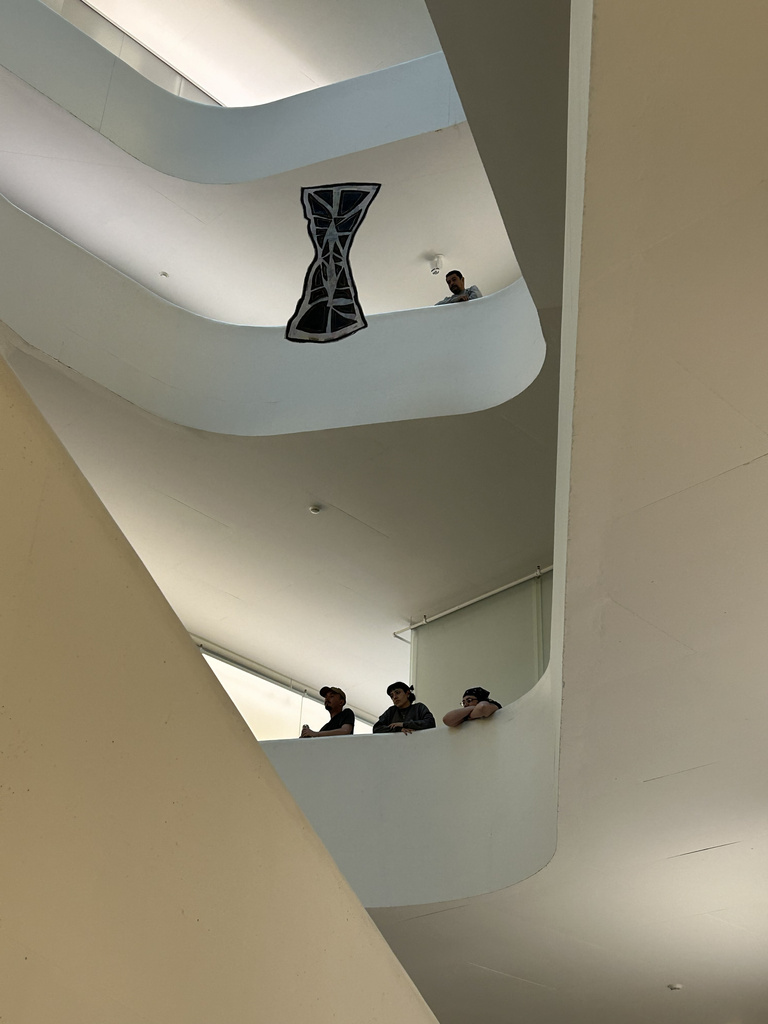 a panel hangs from wires in a white atrium