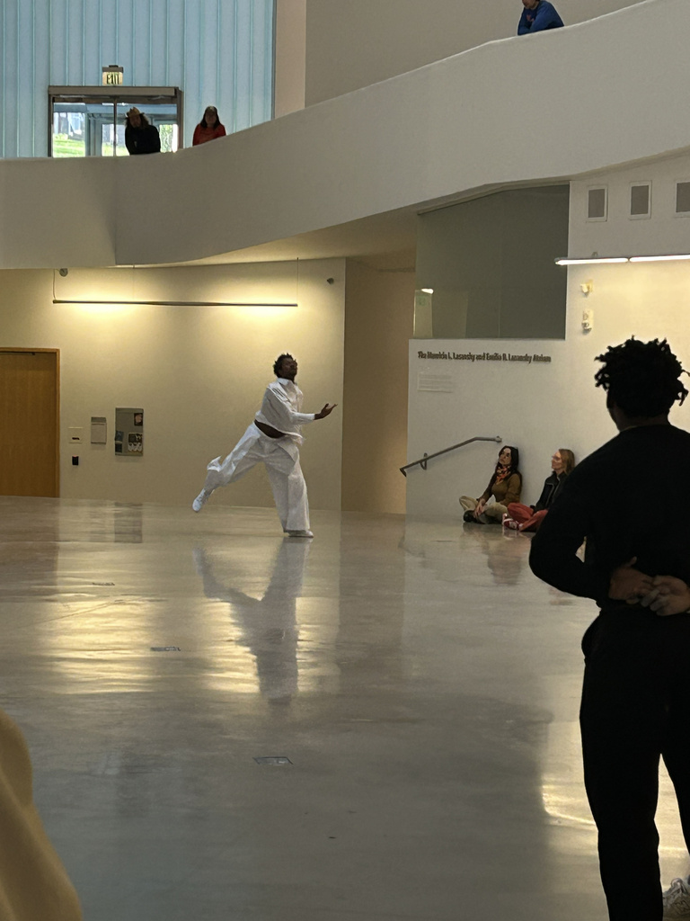 a man dressed in white dances in a white atrium while people watch