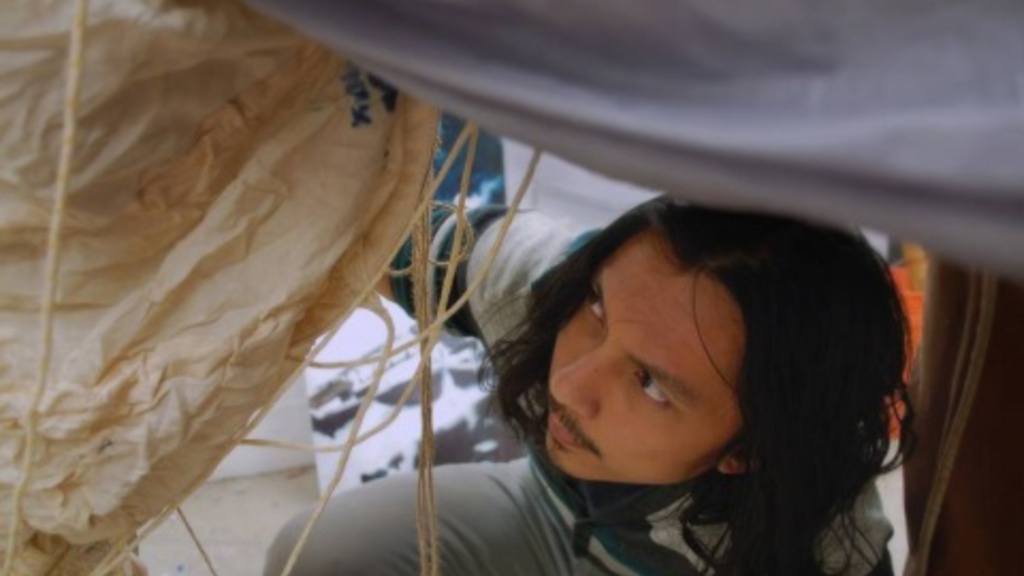 Joe deVera crouches under a tarp