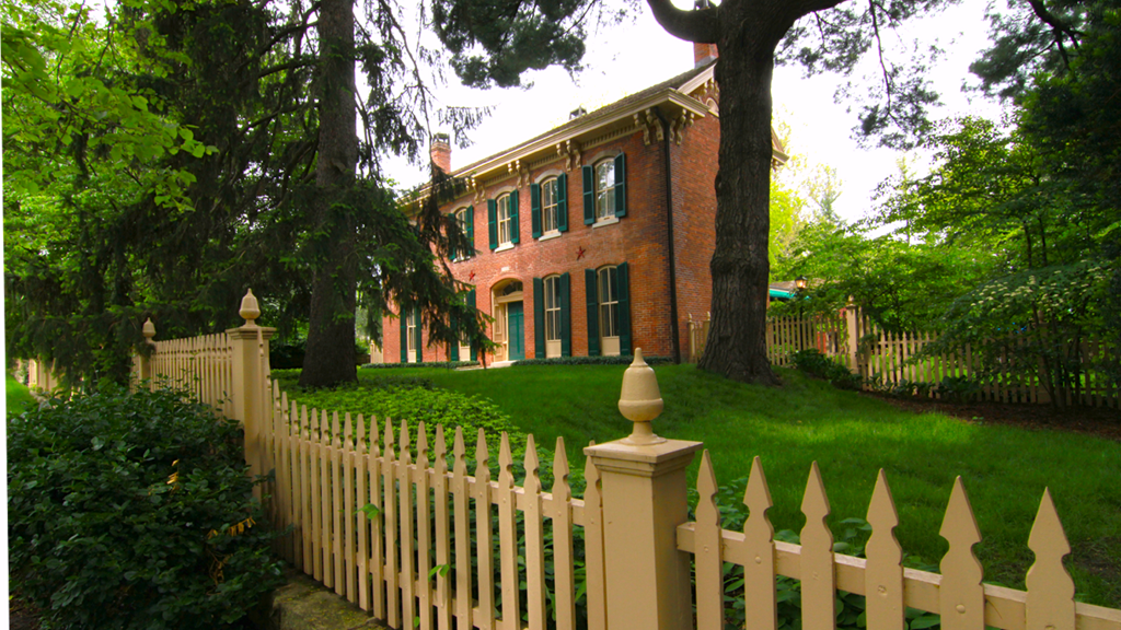 Brick two-story house behind a cream picket fence