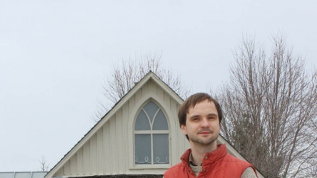 Terry Conrad stands in front of the American Gothic house
