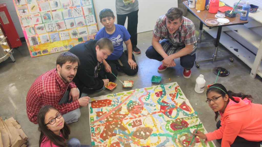 kids paint abstract images on a large canvas on the floor