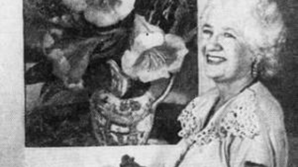 older white woman standing before a painting of flowers