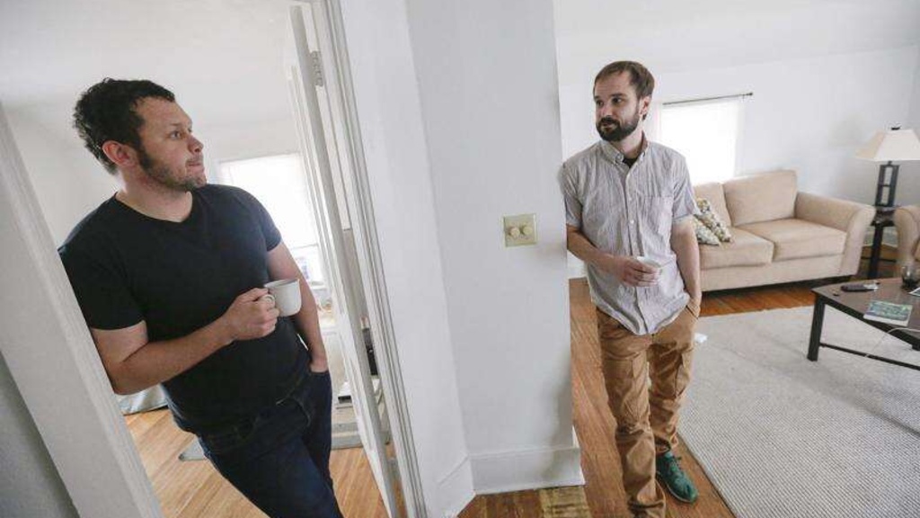 Neal Rock stands with Terry Conrad in an apartment