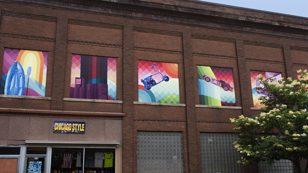 6 abstract murals infill the upper story windows of a brick building